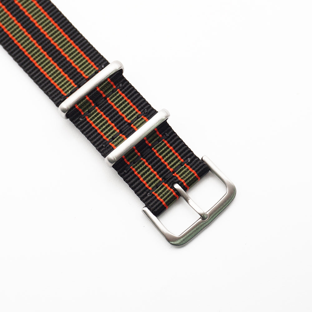 Spännet på ett grön-, röd- och svartrandigt natoband.